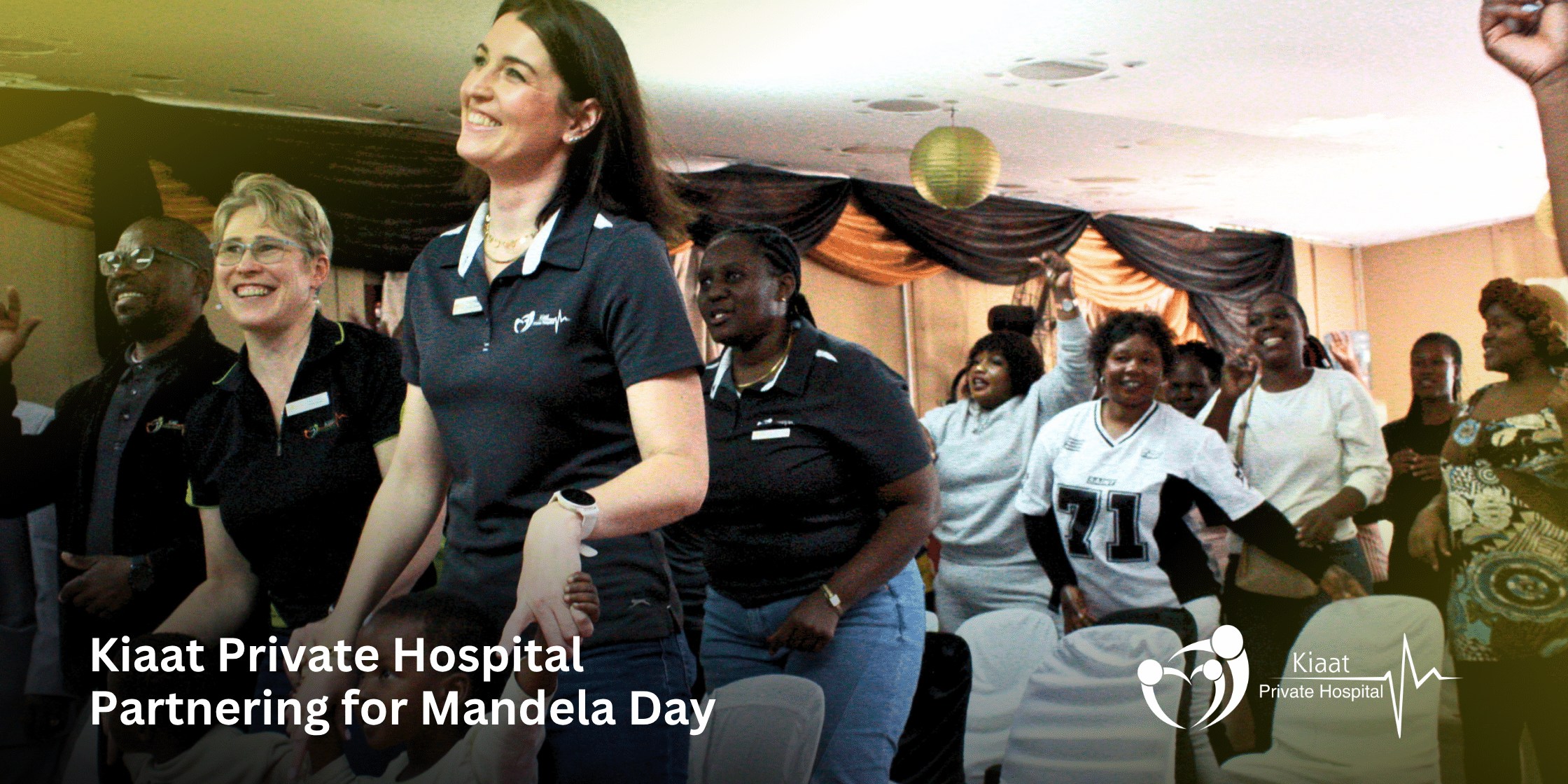 A group of smiling Kiaat Private Hospital staff members dancing and celebrating alongside community members for Mandela Day